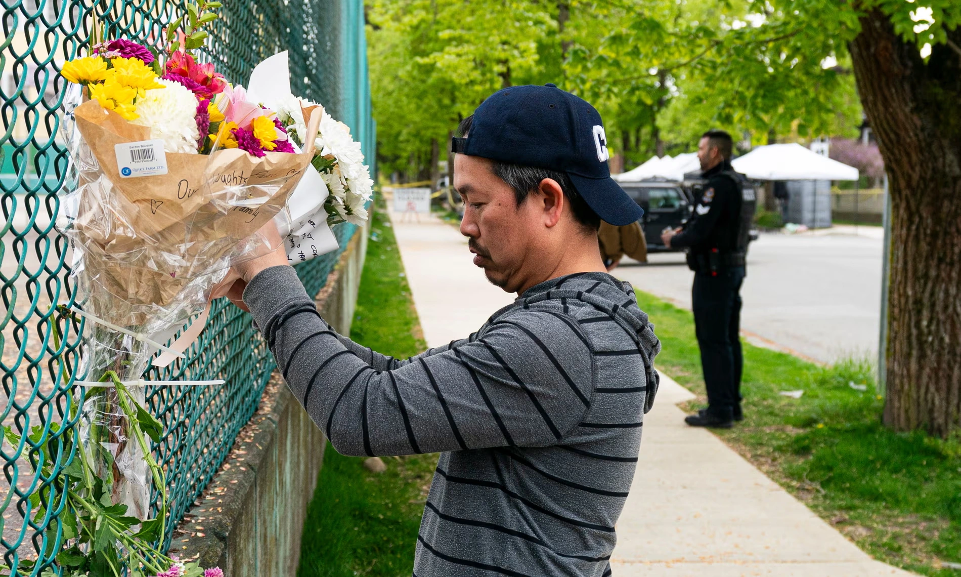 A-man-leaves-flowers-on-a-fence-near-the-location-where-a-vehicle-drove-into-crowd-at-a-street-festival-last-night