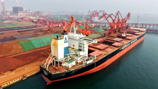 Bulk carrier loading or unloading iron ore at a Chinese port, highlighting international commodity trade and shipping operations.