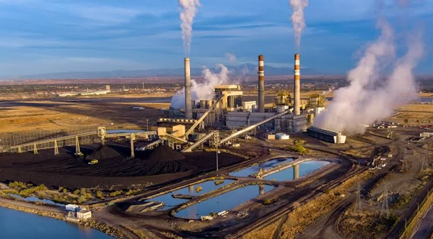 Coal-fired power plant in Colorado featuring large cooling towers, smokestacks, boiler facilities, coal handling infrastructure, and high-voltage transmission lines. The facility represents conventional thermal power generation supplying electricity to the regional power grid.